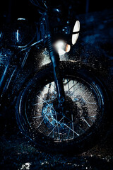 Obraz na płótnie Canvas Vintage styled motorcycle on washing. Blue illumination at night. Splashing water on front wheel with disc brakes. Classic black motorbike. Caferacers style. Maintenance of motor vehicles