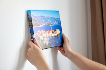 Canvas print with gallery wrap. Woman hangs photography on white wall