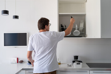 Man in white t shirt washing dishes in the kitchen