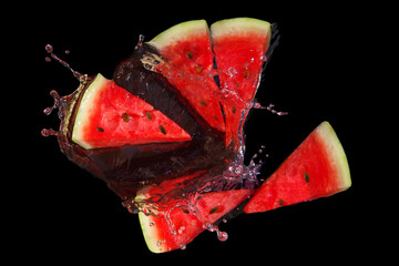 Pieces of red ripe juicy watermelon in splashes on a black background.