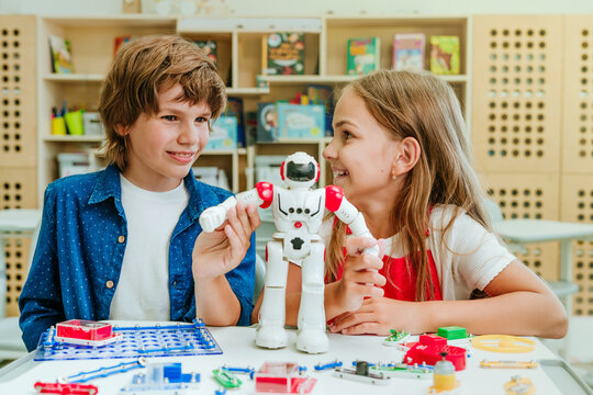 Teenage Boy And Girl Play With Robot During A Lesson In The Classroom.