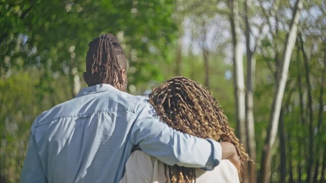 Young black couple walking and kissing in green park, people on a romantic date