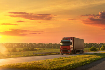 Scenic front view big long heavy semi-treailer truck with sea shipping container driving highway dramatic warm morning evening sunrise sun sky sunset. Cargo transport industry background concept