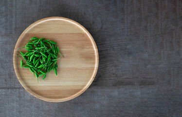 Green hot chilli in a wooden tray on wooden floor