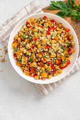 Salad of bulgur, chickpeas and vegetables in a bowl close-up. Salad with chickpea, bulgur, tomato, pepper, cucumber, onion, parsley, and lemon juice. Vegan food, Middle Eastern food.