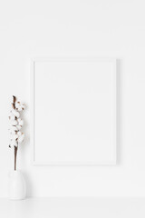 White frame mockup on the wall with a  cotton branch decoration.