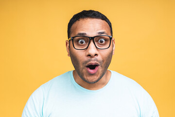 Surprised amazed african american indian man guy in casual isolated over yellow background studio...