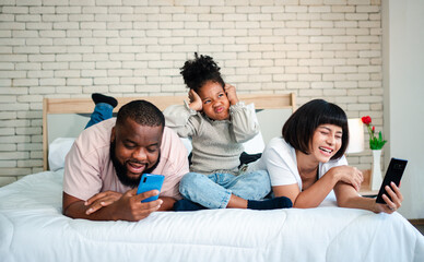 African American girls are not satisfied and sad, sitting in the middle between father and mother. Parents Are using the smartphone and abandoned children. Children need their parents attention.