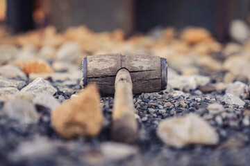 A used meat tenderizer in the stones on the ground