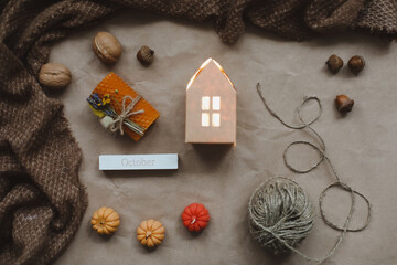 Fototapeta na wymiar Cozy autumn composition with paper house surrounded by autumn leaves, candles and pumpkin top view. Hygge home decor. Halloween and Thanksgiving concept