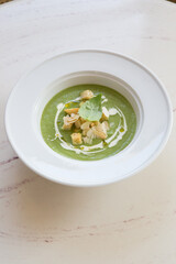 Green vegetarian cream soup served in white plate