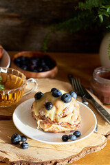 Cinnamon rolls with white chocolate and blueberries. Brioche. Side view, wooden background, icing sugar, cocoa, yeast buns.