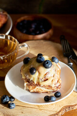 Cinnamon rolls with white chocolate and blueberries. Brioche. Side view, wooden background, icing sugar, cocoa, yeast buns.