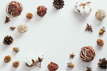 Autumn composition. Frame made of cotton, pine cones, anise, ball decorations on white background. Flat lay, top view, copy space.