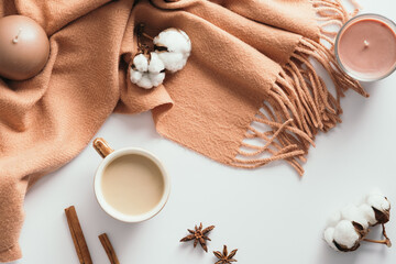 Autumn composition. Flat lay coffee cupm candles, brown scarf, cotton, cinnamon sticks, anise on white background. Hygge cozy home desk table.