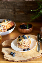 Cinnamon rolls with white chocolate and blueberries. Brioche. Side view, wooden background, icing sugar, cocoa, yeast buns.