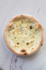 Fresh baked round pizza four cheeses on a cafe table