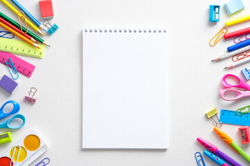 Blank paper notepad mockup with colorful school stationery on white background. Flat lay, top view, copy space. Back to school concept,