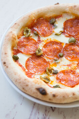 Whole round neapolitan pepperoni pizza served on a table