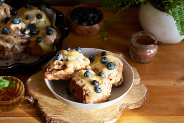 Cinnamon rolls with white chocolate and blueberries. Brioche. Side view, wooden background, icing sugar, cocoa, yeast buns.
