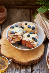 Cinnamon rolls with white chocolate and blueberries. Brioche. Side view, wooden background, icing sugar, cocoa, yeast buns.