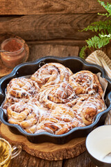 Rose cinnamon rolls. Brioche. Side view, wooden background, icing sugar, cocoa, yeast buns.