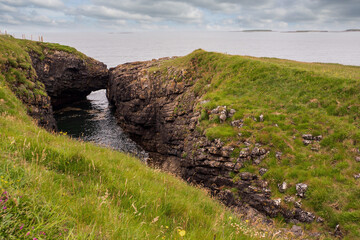 Two rocks by the ocean close to each other, one in a shape of beaver, illusion of kiss