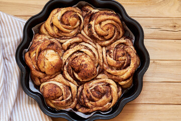 Rose cinnamon rolls. Brioche. Top view, wooden background, cocoa, yeast buns.