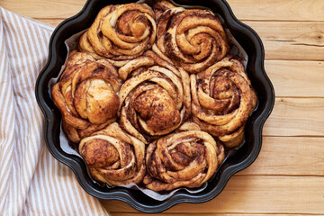 Rose cinnamon rolls. Brioche. Top view, wooden background, cocoa, yeast buns.
