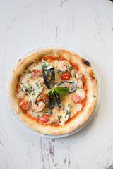 Whole neapolitan seafood pizza served on a marble table