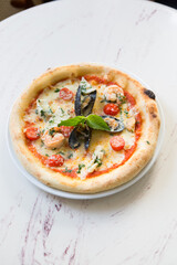 Whole neapolitan seafood pizza served on a marble table