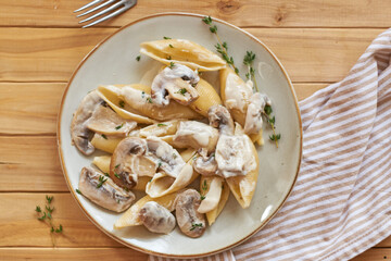 Creamy pasta with mushrooms and thyme. Top view, wooden background.