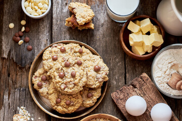 Oatmeal Chocolate Chip Cookies. Wooden background, top view, eggs, oatmeal, flour, chocolate chips, ingredients, milk, butter, rustic.