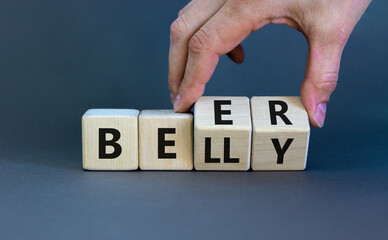 Beer belly symbol. Doctor turns wooden cubes with words 'beer belly'. Beautiful grey table, grey...