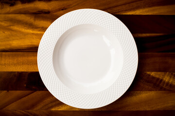A large white ceramic plate is placed on a wooden background.