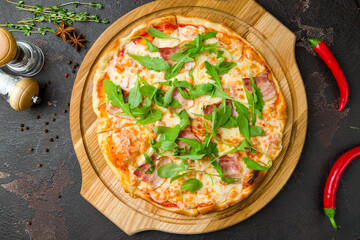 Pizza with bacon and aragula on brown stone table top view