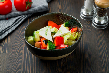 Greek salad with feta on dark wooden table
