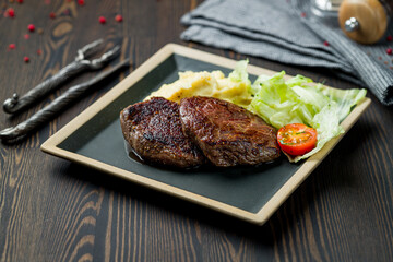 medallions of beef with mashed potatoes on dark wooden table