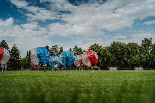People playing in Bubble Football. Zorbing bumper football soccer on a green field