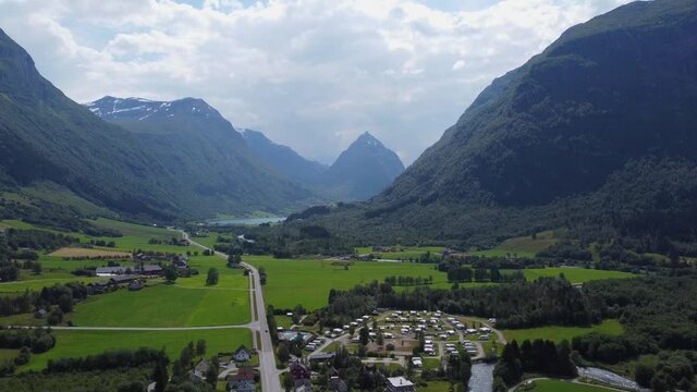Village and valley in Byrkjelo with pointy mountain Eggjenibba in background - Reverse summer day aerial Norway