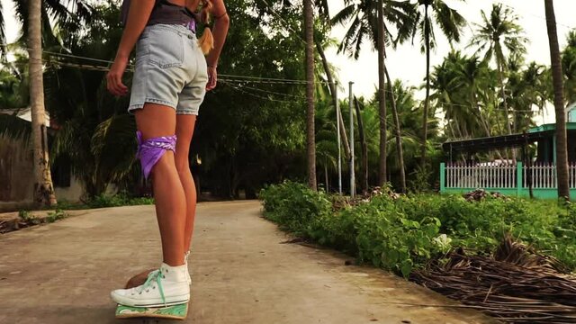 Close up shot of long legged woman riding a surkskate in a rural town in Vietnam