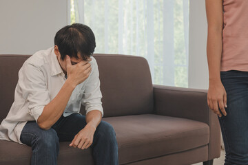 Obraz premium Unhappy young asian couple fights on couch, relationship is in trouble. Different people are angry and use emotions at each other. Wife has an expression of disappointment and upset with her husband.