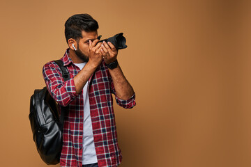 Hindu photographer with backpack and camera in casual close on pastel background copy space