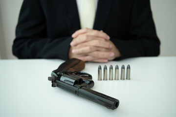 Businessman or agent in black suit showing the revolver handgun on the table.