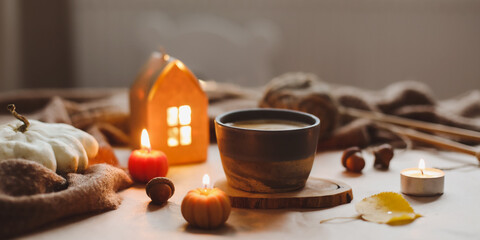 Autumn cozy home interior with a cup, candles, plaid. Hygge home decor. Halloween and Thanksgiving concept 