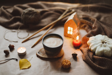 Autumn cozy home interior with a cup, candles, plaid. Hygge home decor. Halloween and Thanksgiving concept 