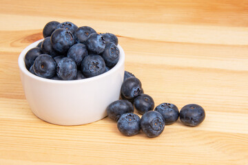 Fresh blueberry in white dish on wooden background copyspace