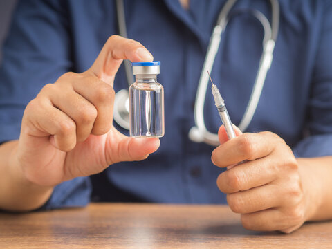 A doctor is holding a vaccine bottle and syringe. Vaccine for prevention and treatment from virus infection. Close-up photo. Concept of medical and the fight against the virus