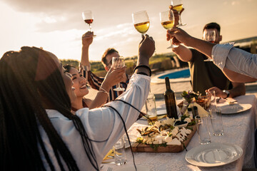 Group of friends at reunion eating and drinking wine outdoor.