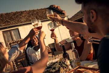 Group of friends at reunion eating and drinking wine outdoor.